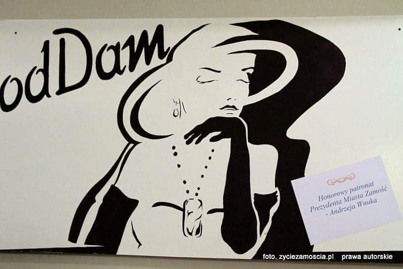 Grafika czarno-biała przedstawia elegancką kobietę w kapeluszu i długich rękawiczkach. Nad kapeluszem czarny napis: odDAm