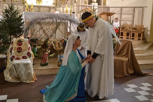 Kobieta klęczy przed mężczyzną a ten pochyla się nad nią. Kobieta jest przebrana za Maryję a mężczyzna za anioła.