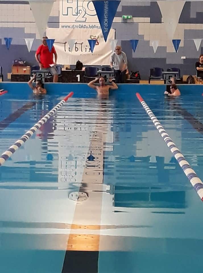 Mężczyźni w basenie są pod stopniami do skoku. Każdy z nich jest w wyznaczonym torze.