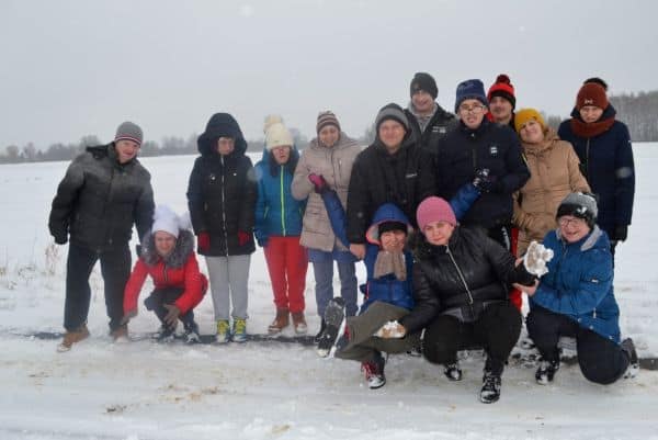 Zdjęcie grupowe czternastu osób na tle zimowej scenerii. Liczna grupa pozuje stojąc a cztery kucając.