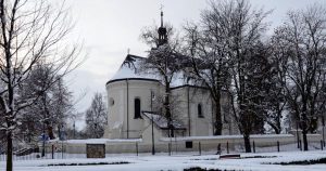 Widok na biały kościół otoczony kilkoma drzewami w zimowej scenerii