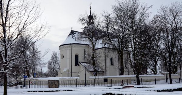 Widok na biały kościół otoczony kilkoma drzewami w zimowej scenerii