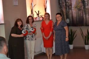 Cztery panie pozują do pamiątkowego zdjęcia. Dwie z nich trzymają w ręku rzeźbę Serce Dobroci.