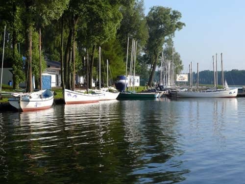 Na zdjęciu na spokojnej stoją zacumowane do brzegu żaglówki.