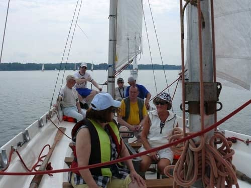 Na zdjeciu uczestnicy rejsu siedzą w żaglówce.