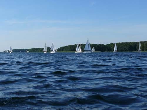 Panoramiczne ujęcie z linii wody na stado płynących żaglówek
