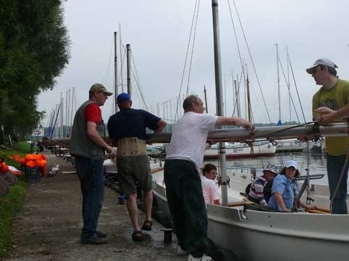 Na zdjęciu grupa mężczyzn naprawia maszt?