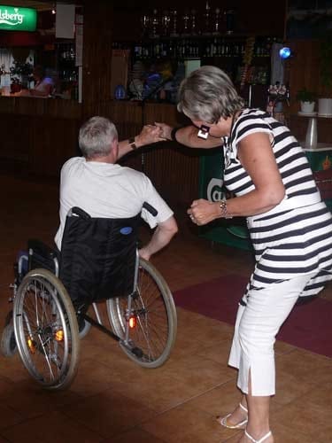 Na zdjęciu kobieta tańczy z mężczyzną na wózku.