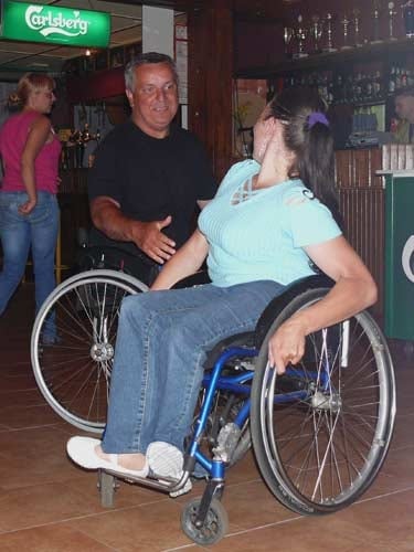 Na zdjęciu kobieta i mężczyzna tańcz ze sobą. Oboje poruszają się na wózkach. Mężczyzna jest uśmiechnięty.