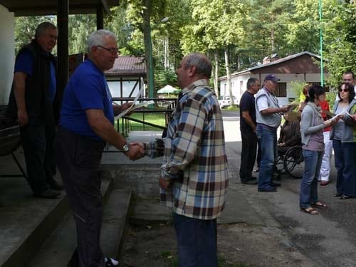 Na zdjęciu mężczyzna odbiera dyplom od organizatora wyjazdu.