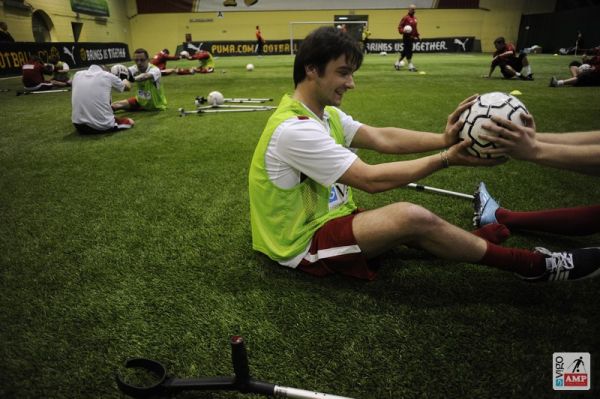 Na zdjęciu piłkarze siedzący przodem do siebie wzajemnie próbują przepchnąć piłkę do przeciwnika trzymając na niej wyprostowane ręce. 