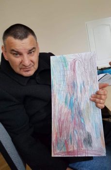 Na zdjęciu Jarosław Kamiński prezentuje swoje dzieło - żyrafę namalowaną na papierze.