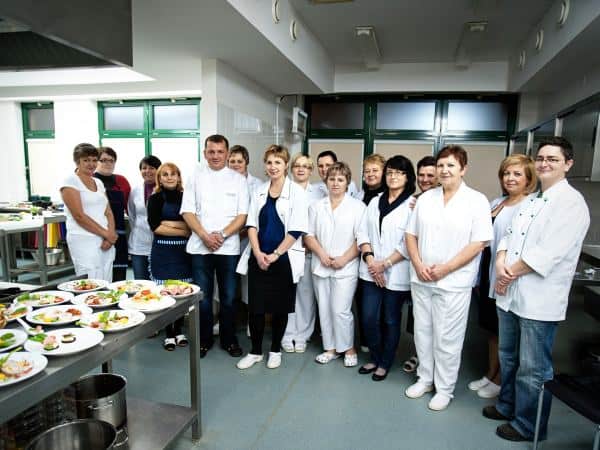 Grupa kucharzy pozuje w kuchni do zdjęcia.