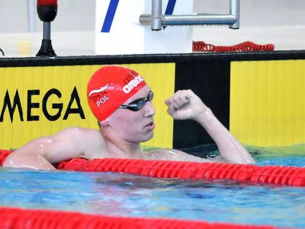 Artur Pióro z gestem zwycięstwa zaciśniętej pięści w basenie.