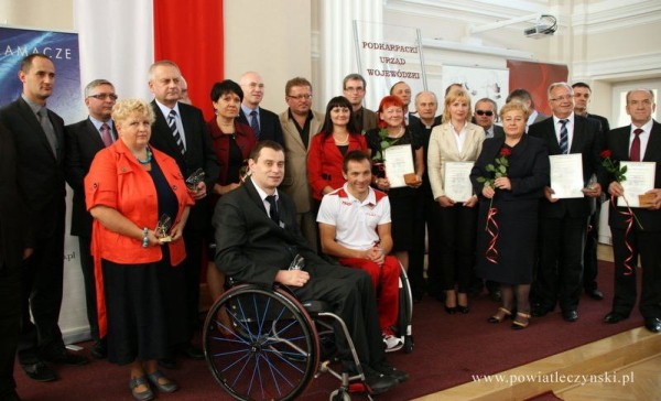Grupa ludzi w tym mężczyzna pozuje do zdjęcia.na uroczystej gali rozdania nagród.