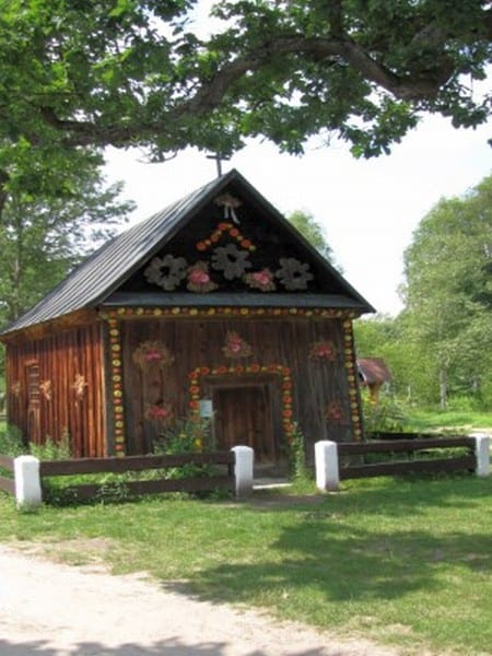 Drewniana kapliczka bogato zdobiona w ornamenty i folklorystyczne wzory.