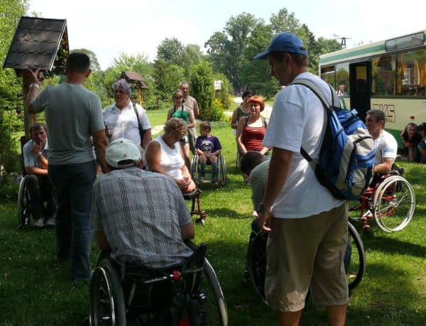 Grupa słucha przewodnika wycieczki stojąc w kręgu wokół niego.