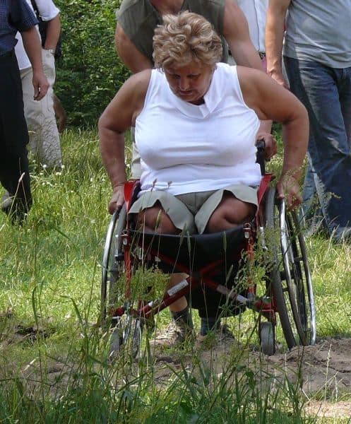 Kobieta na wózku jedzie przez zapiaszczoną ścieżkę