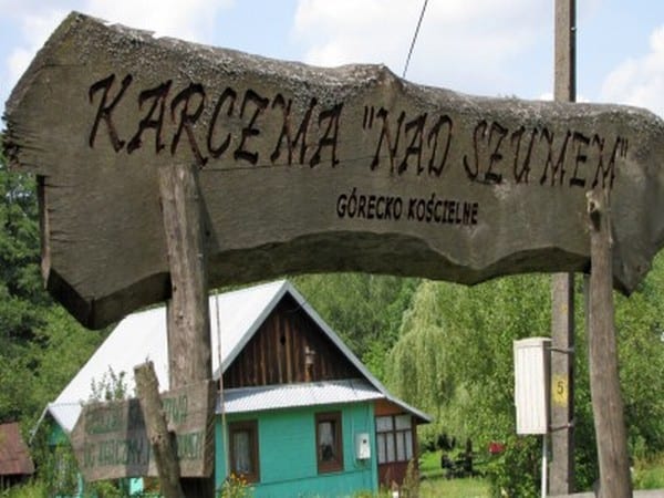 Drewniany szyld karczmy "Nad Szumem" z nieociosanej deski drzewa