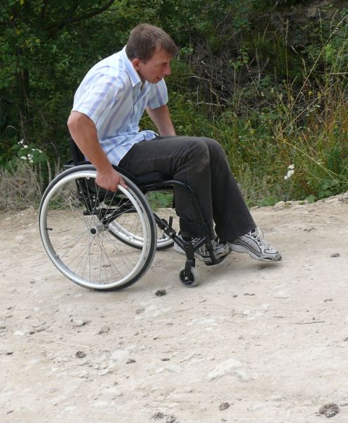 Mężczyzna na wózku podjeżdża pod lekkie wzniesienie,