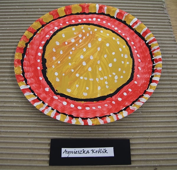 Talerz z “Tanganiki”. Rękodzieło z użyciem papierowego talerza pomalowanego w kolorowe wzory pomarańczowo żółto czarne.