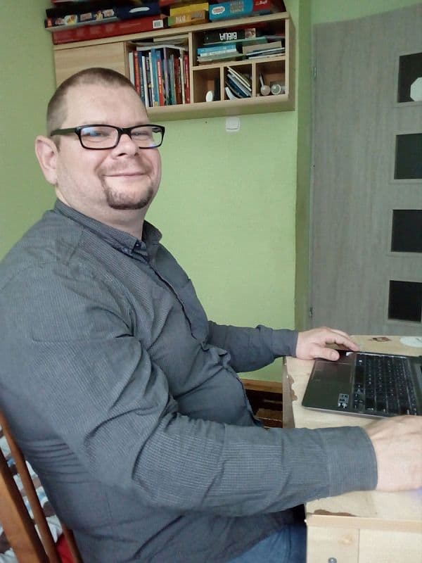 Andrzej-Czerminski przy laptopie, uśmiecha się do zdjęcia.