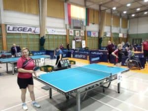 Hala sportowa, zawody gry w ping-ponga. Katarzyna Kowalik przy stole tenisa stołowego pozuje do zdjęcia z rakietką w dłoni.