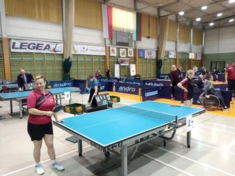 Hala sportowa, zawody gry w ping-ponga. Katarzyna Kowalik przy stole tenisa stołowego pozuje do zdjęcia z rakietką w dłoni.