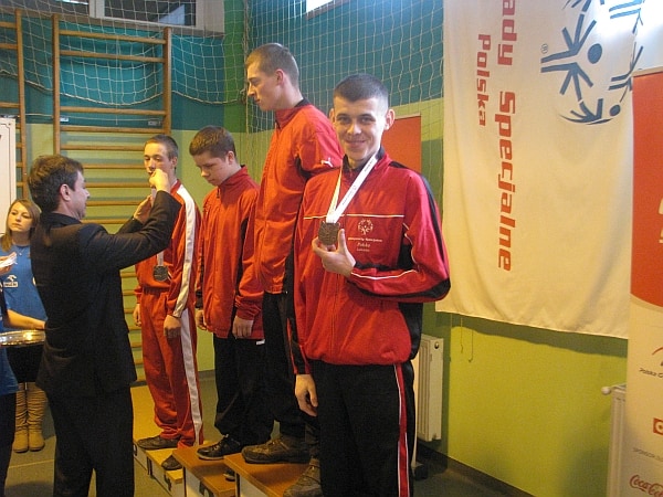 Bogusław Cisło prezentuje brązowy medal do zdjęcia stojąc na trzecim miejscu podium.