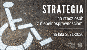 Biały symbol niepełnosprawnego wózka inwalidzkiego namalowany na asfalcie. Obok napis: Strategia na rzecz Osób z Niepełnosprawnościami na lata 2021-2030