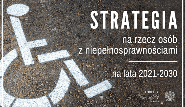 Biały symbol niepełnosprawnego wózka inwalidzkiego namalowany na asfalcie. Obok napis: Strategia na rzecz Osób z Niepełnosprawnościami na lata 2021-2030