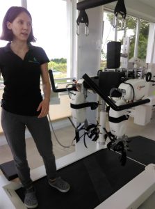 Kobieta stoi na specjalistycznym urządzeniu rehabilitacyjnym.