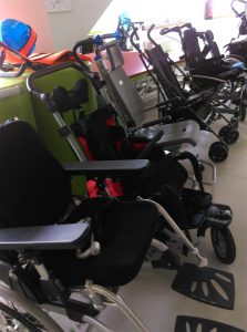 Kilka wózków ustawionych w rzędzie. Wśród nich wózki dla niepełnosprawnych.