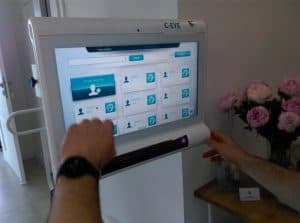 Ekran urządzenia jest włączony. Jedną ręką człowiek trzyma go a druga jest tuz przed ekranem w pozycji pięści.