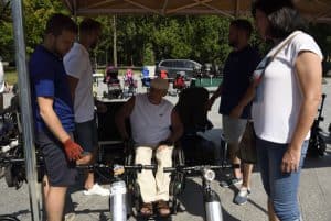 Ludzie są pod zadaszonym namiotem eventowym. Jeden z mężczyzn jest na wózku.