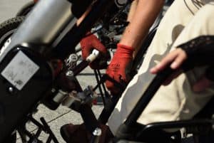 Na zdjęciu jest dłoń w czerwonej rękawiczce z przyblizeniem na elementy maszyny.