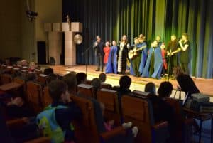 Ludzie stoją na scenie. W tle jest widowni.