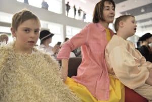 Ludzie siedzą na widowni. Kobieta trzyma chłopca na kolanach