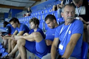 Mężczyźni siedzą na trybunach ubrani cali na niebiesko.