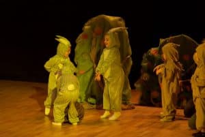 Dzieci w stroju skrzatów są na scenie. Twarze ich sa zwrócone ku sobie.