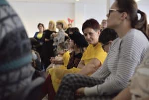 Jest widownia. Ludzie siedzą na krzesłach. Patrzą się przed siebie