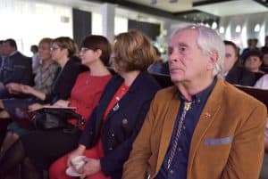 Ludzie siedzą na widowni. Twarze są zwrócone przed siebie.