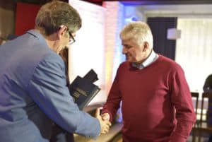 Mężczyzna podaje dłoń starszemu mężczyźnie, który się uśmiecha.