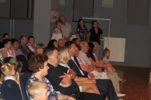 Ludzie siedzą na widowni. Patrzą na wprost siebie.