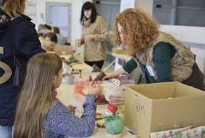 Ludzie pochylają się nad stołem. Na stole są rękodzieła.