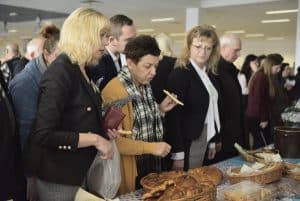 Ludzie pochylają się nad stołem. Na stole są potrawy.