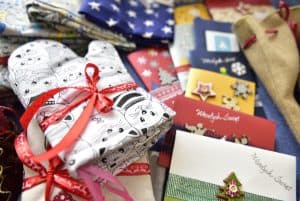 Na zdjeciu są ręcznie przygotowane upominki. Karki świąteczne i rękawica kucharska owinieta wstążką w kokardkę.