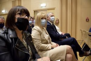 Kobiety i mężczyzna siedzą w pierwszym rzędzie tuż przed scena. Wszyscy patrzą poza obiektyw.