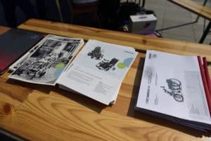 Na stole leżą ulotki i kolorowe kartki.