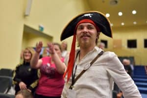 Mężczyzna z kapeluszem pirata. W tle inni ludzie siedzący na widowni.